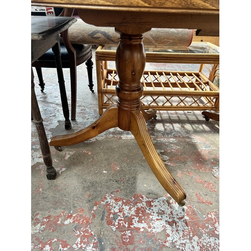 63 - A pine extending dining table with twin pedestal supports and castors