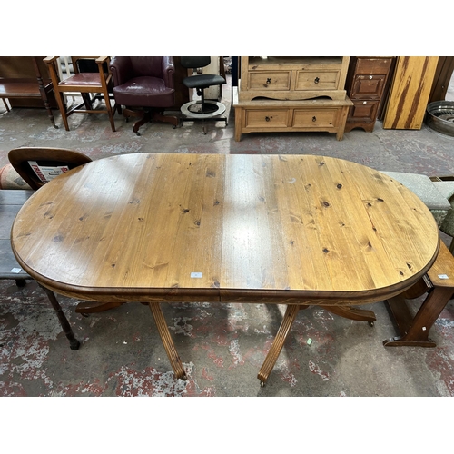 63 - A pine extending dining table with twin pedestal supports and castors