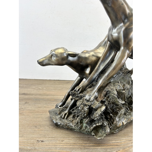 689 - A modern bronze effect figurine of two sighthounds - approx. 31cm high x 38cm long