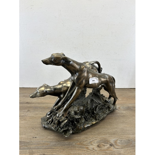 689 - A modern bronze effect figurine of two sighthounds - approx. 31cm high x 38cm long