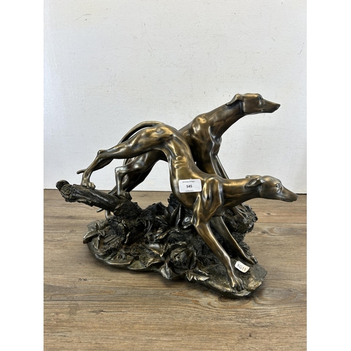 689 - A modern bronze effect figurine of two sighthounds - approx. 31cm high x 38cm long