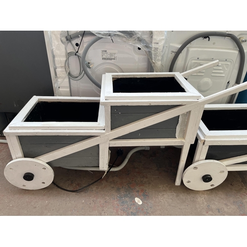 723 - Two grey and white painted wooden two step wheelbarrow planters - largest approx. 64.5cm high x 38cm... 