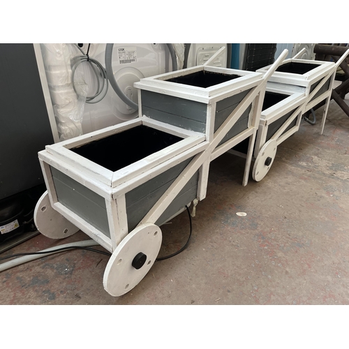 723 - Two grey and white painted wooden two step wheelbarrow planters - largest approx. 64.5cm high x 38cm... 