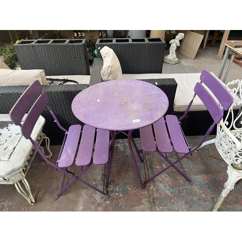 790 - A three piece purple metal bistro set comprising two folding chairs and table