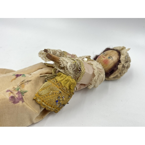 1475 - An antique Queen Anne type hand painted and carved wooden doll with hand decorated silk clothing - a... 