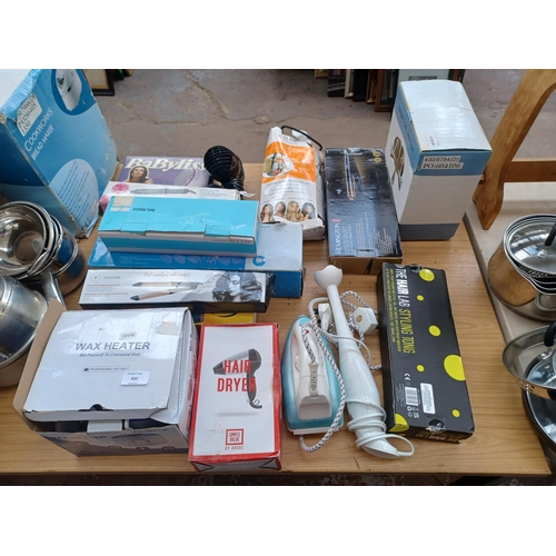 932 - Fifteen items to include steam iron, hand blender, boxed halogen spot light, wax heater, body massag... 