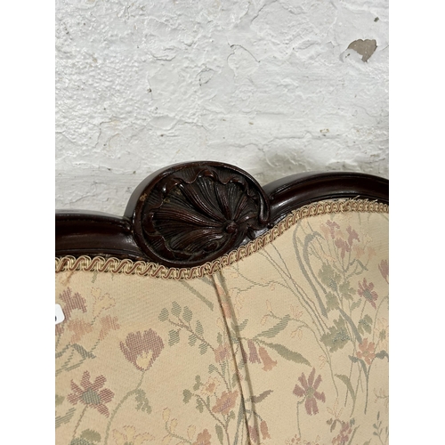 185 - An Edwardian carved mahogany and floral upholstered two seater parlour sofa with cabriole supports a... 