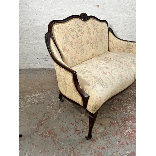 185 - An Edwardian carved mahogany and floral upholstered two seater parlour sofa with cabriole supports a... 