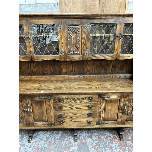 33 - A Webber Furniture carved oak dresser with four upper leaded glass doors, four cupboard doors and fo... 