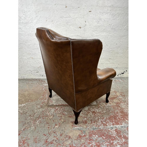 42 - A brown leather wingback armchair with cabriole supports