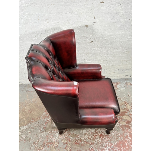 44 - An oxblood leather Chesterfield wingback armchair with cabriole supports