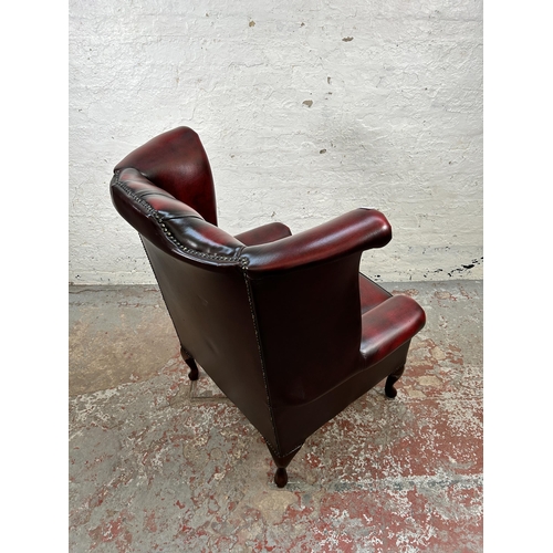 44 - An oxblood leather Chesterfield wingback armchair with cabriole supports