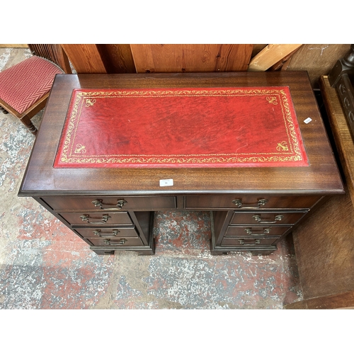 51 - A 19th century style mahogany kneehole desk with red leather writing surface, six short drawers, two... 