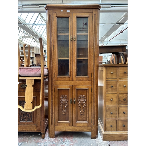 61 - An Edwardian style carved oak free standing corner cabinet
