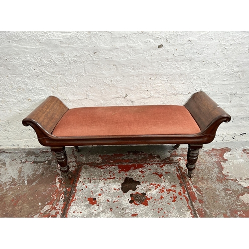 105 - A Regency mahogany and pink fabric upholstered window seat with turned supports and castors