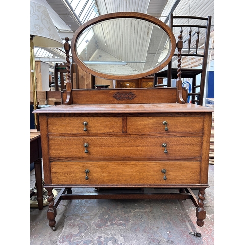 114 - An early 20th century oak dressing table with upper oval bevelled edge mirror, two short drawers, tw... 