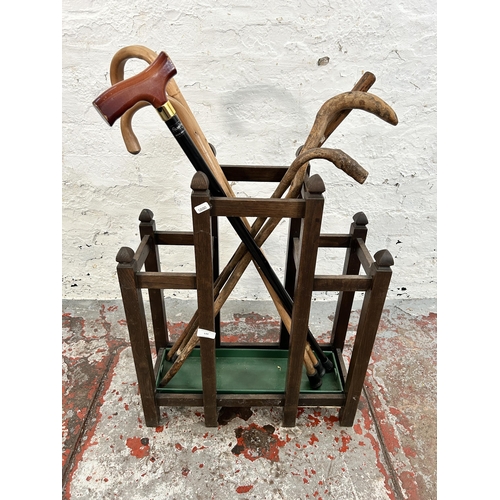 133 - An early 20th century oak three section stick stand with green metal drip tray and contents