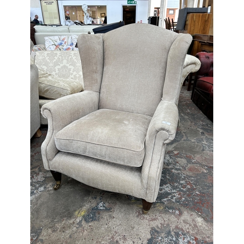 246 - A Victorian style fabric upholstered wingback armchair with mahogany supports and brass castors