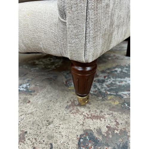 246 - A Victorian style fabric upholstered wingback armchair with mahogany supports and brass castors