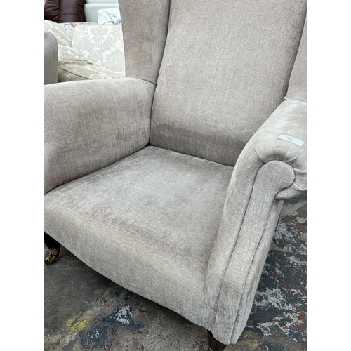 246 - A Victorian style fabric upholstered wingback armchair with mahogany supports and brass castors