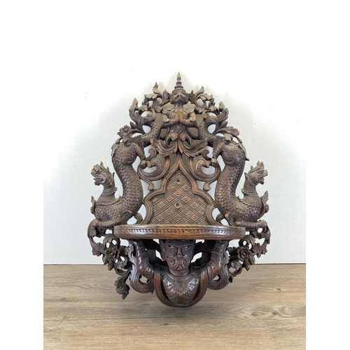 610 - A Burmese heavily carved hardwood wall bracket - approx. 56cm high x 43cm wide