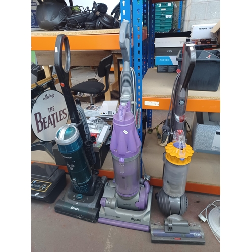 874 - Three upright bagless vacuum cleaners, one Dyson DC07, one Dyson DC40 and one Hoover