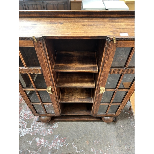 14 - An Art Deco oak bookcase with two glazed doors and baluster supports