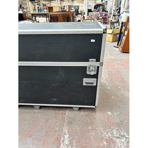 142 - A black plastic and grey metal flight case - approx. 119cm high x 222cm long x 62cm wide