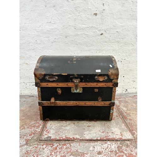 143 - An early 20th century black fibreboard dome top travel trunk with copper and oak banding and brown l... 