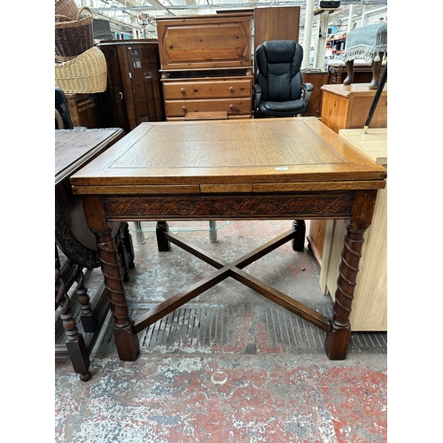 147 - A 1930s carved oak draw leaf dining table with barley twist supports and lower stretcher