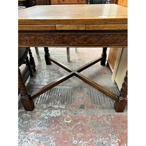 147 - A 1930s carved oak draw leaf dining table with barley twist supports and lower stretcher