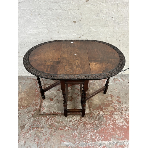 149 - A Macclesfield School of Carving carved oak drop leaf gate leg oval dining table on barley twist sup... 