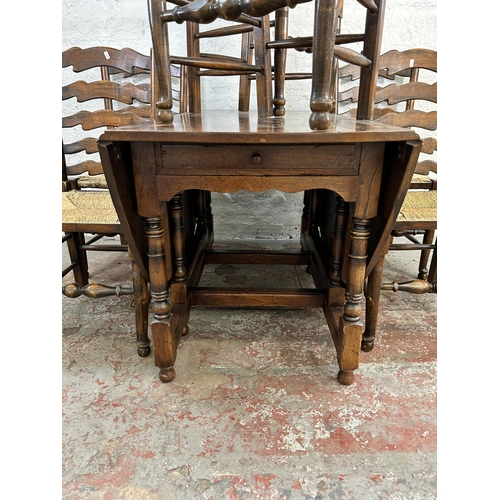 28 - A 17th century style elm and oak drop leaf gate leg oval dining table and six elm and rush seated la... 