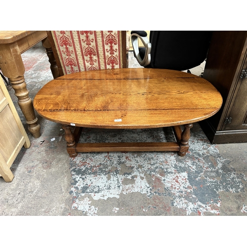 41 - A 17th century style solid oak oval coffee table with turned supports and lower stretcher