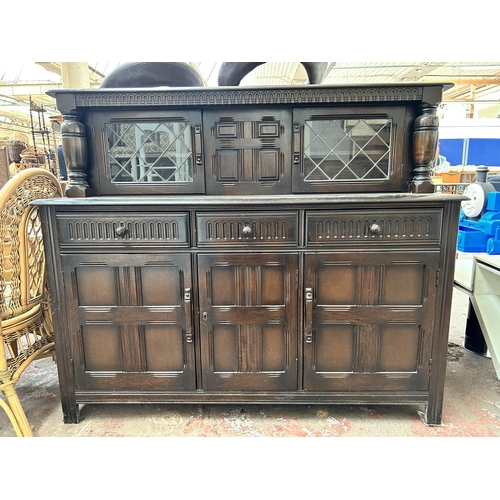 52 - A carved oak court cupboard with two upper leaded glass doors, three drawers and three cupboard door... 
