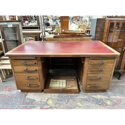 188 - A mid 20th century walnut veneered twin pedestal office desk with seven drawers and red leatherette ... 