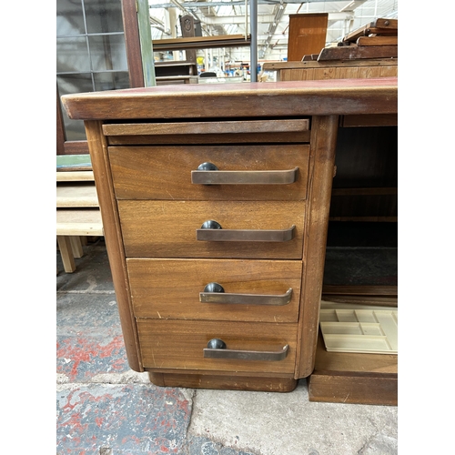 188 - A mid 20th century walnut veneered twin pedestal office desk with seven drawers and red leatherette ... 