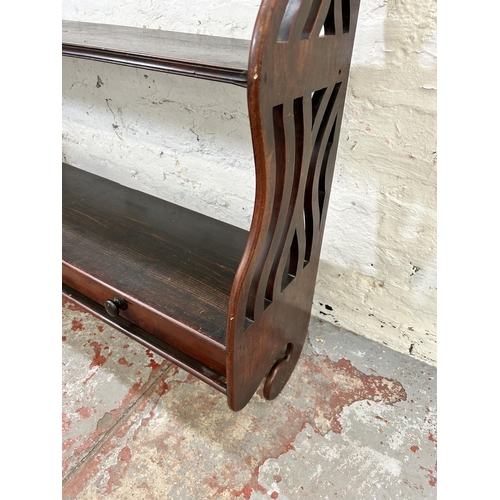 214 - A mahogany three tier wall mountable shelving unit with stained pine shelves and carved fretwork