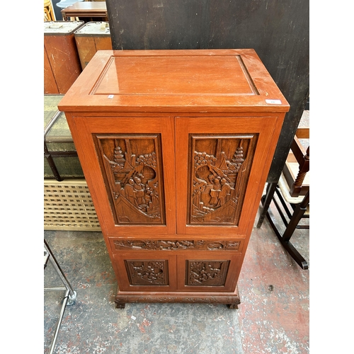 236 - A Chinese carved hardwood stereo cabinet with four cupboard doors and fitted interior