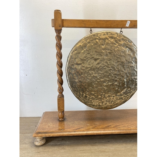 450 - A brass dinner gong on oak barley twist stand with beater - approx. 60cm high x 68cm wide x 25cm dee... 