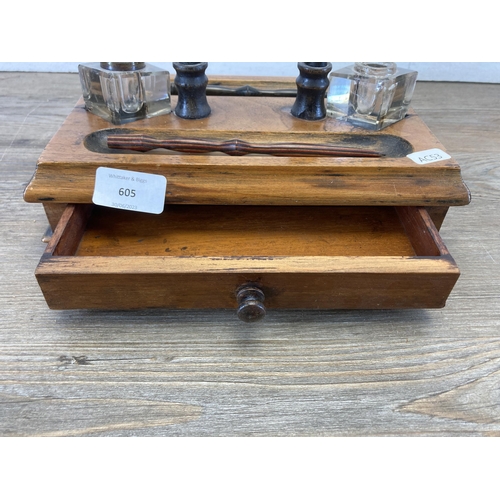 605 - An early 20th century walnut inkwell stand with single drawer and two glass inkwells