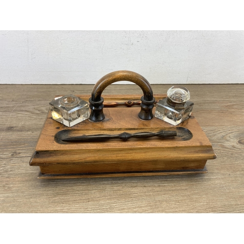 605 - An early 20th century walnut inkwell stand with single drawer and two glass inkwells