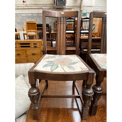 126 - A 1930s carved oak draw leaf dining table with baluster supports and four dining chairs