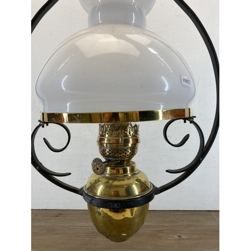 619 - A late 19th/early 20th century brass and wrought iron hanging oil lamp with milk glass shade and cle... 