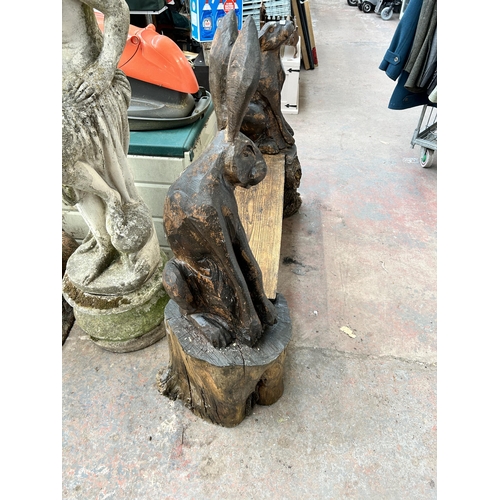 1006 - A heavily carved pine tree trunk garden bench in the form of two hares