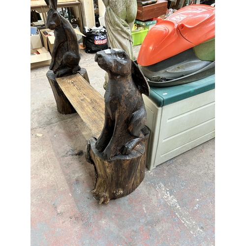 1006 - A heavily carved pine tree trunk garden bench in the form of two hares