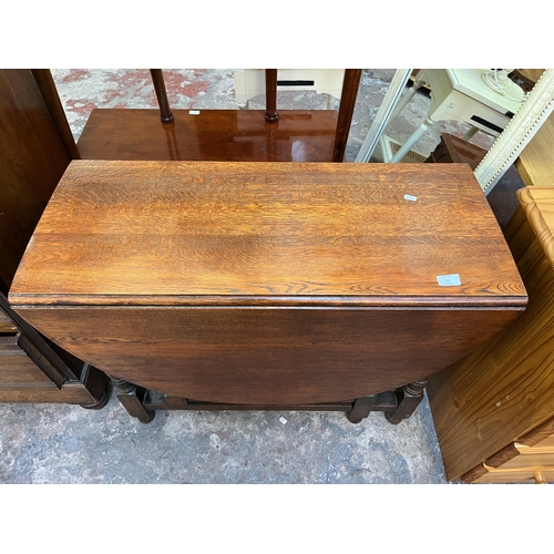 65 - An oak drop leaf gate leg oval dining table