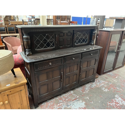 82 - A carved oak court cupboard with two upper leaded glass doors, three drawers and three cupboard door... 