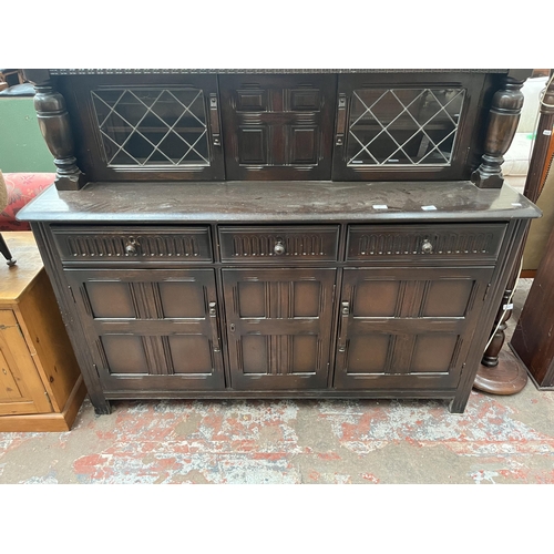 82 - A carved oak court cupboard with two upper leaded glass doors, three drawers and three cupboard door... 