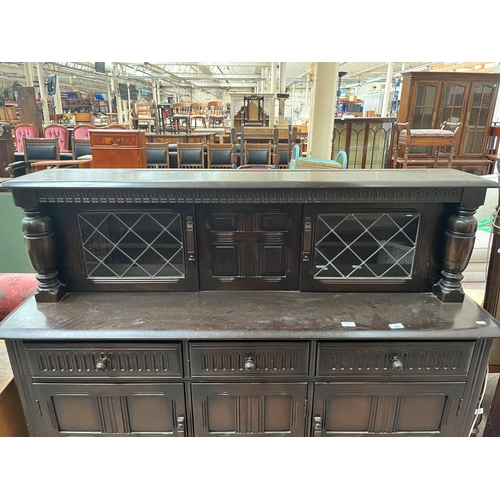 82 - A carved oak court cupboard with two upper leaded glass doors, three drawers and three cupboard door... 